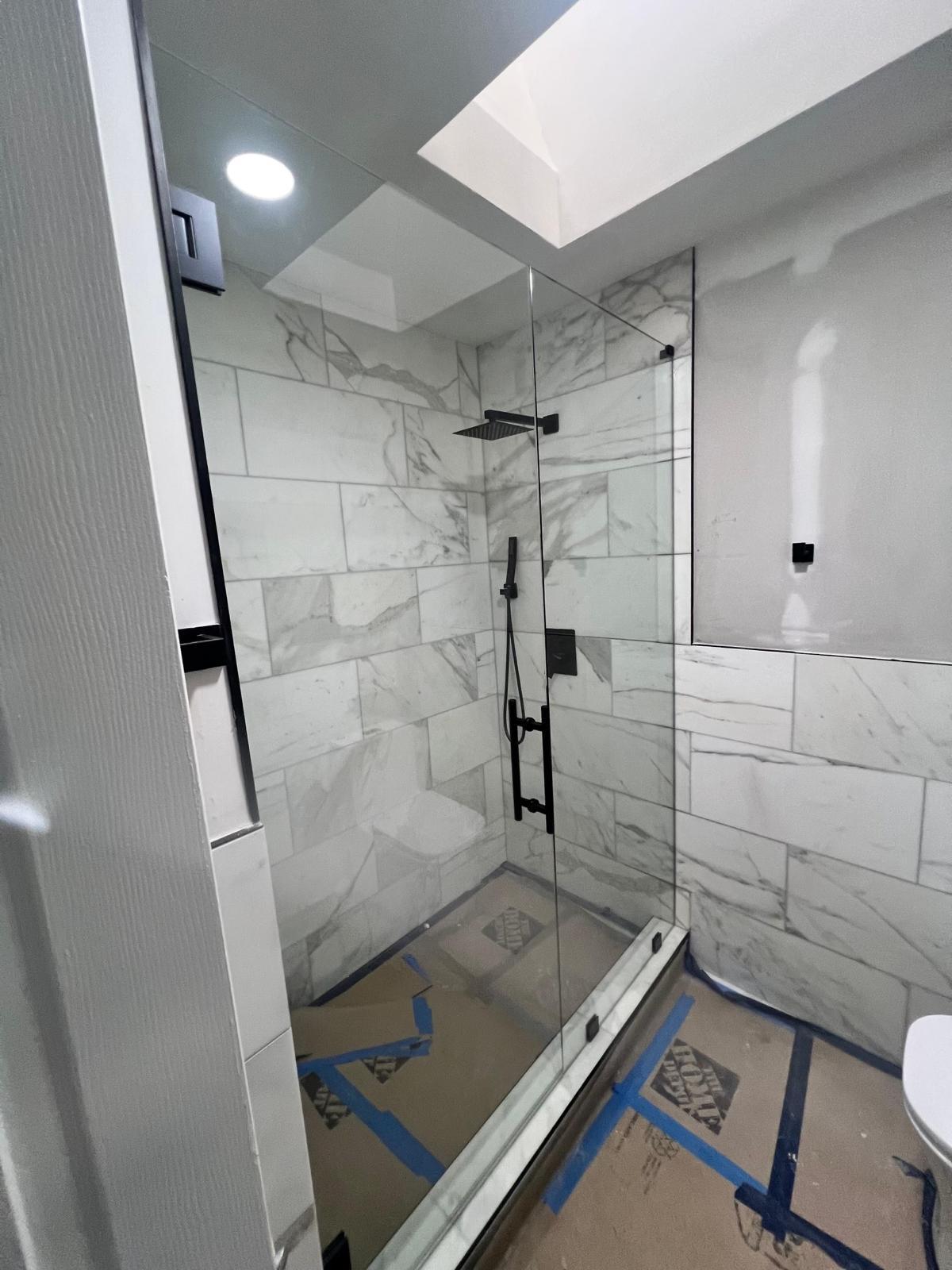 Marble tile shower with glass door and rain showerhead