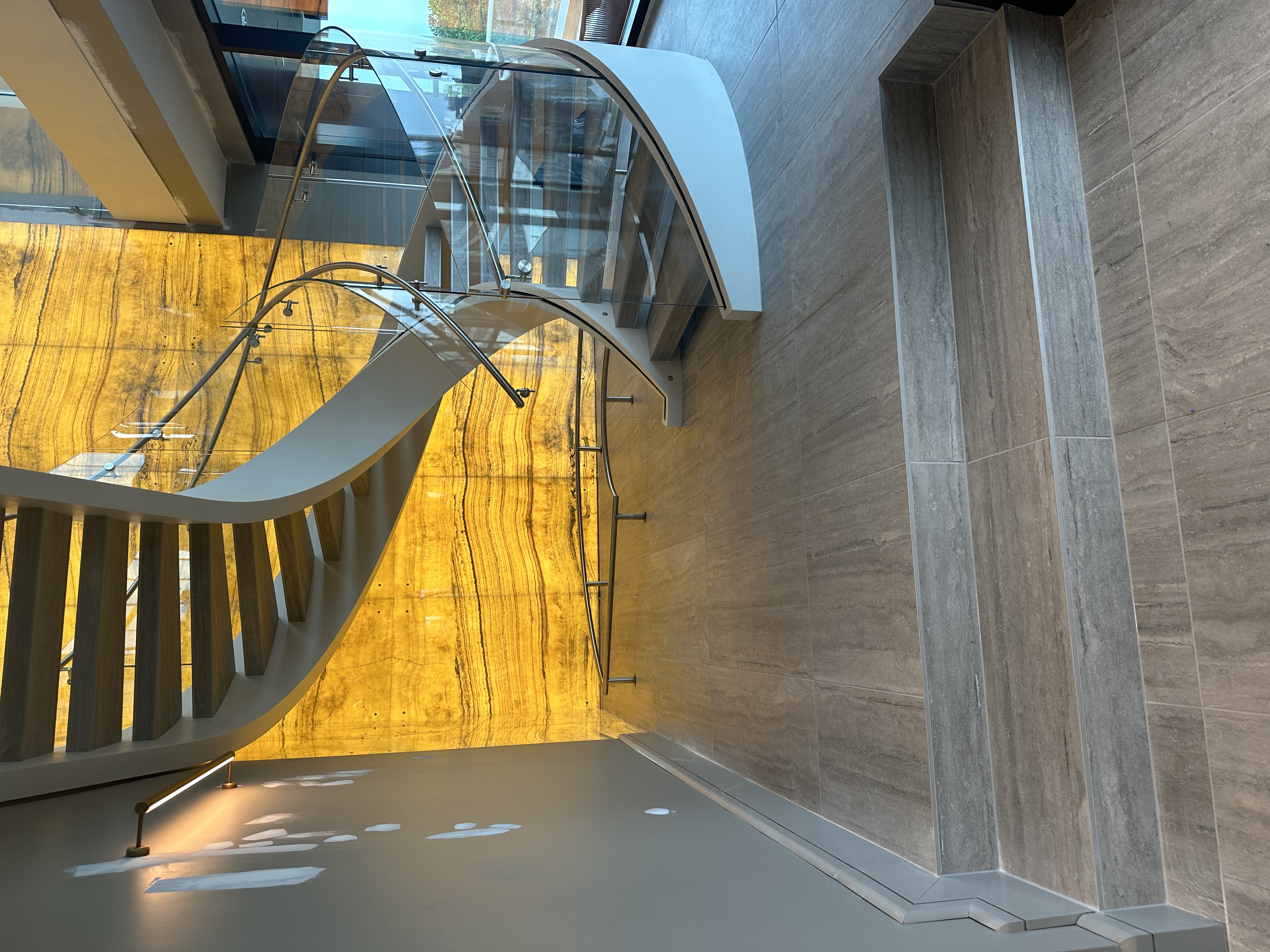 Luxury staircase with backlit onyx stone and large format tile walls